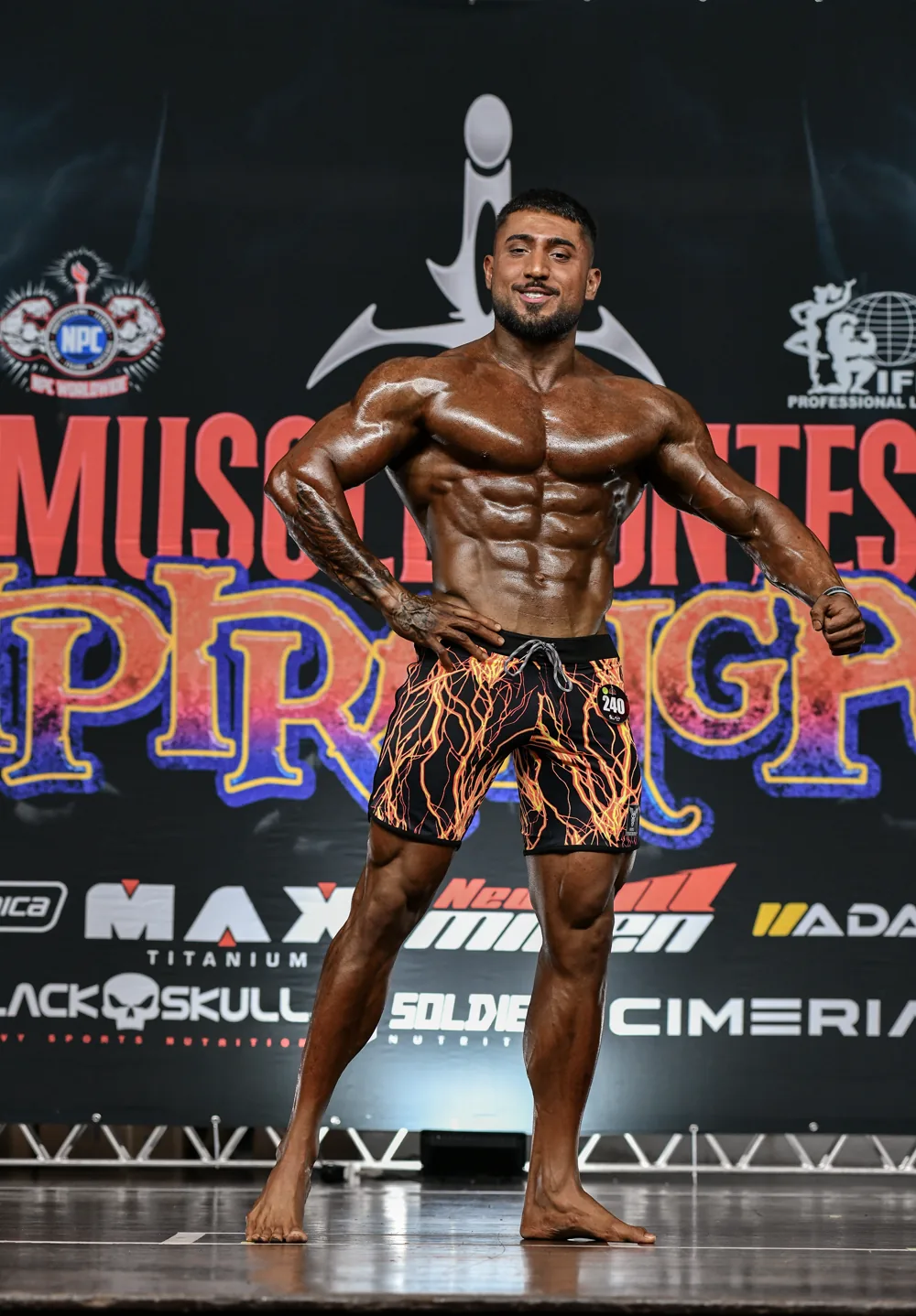 Davi Frois posando no palco durante competição de fisiculturismo